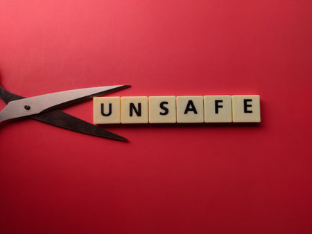 Scissors and toys letters with the word UNSAFE on a red backgroundの写真素材
