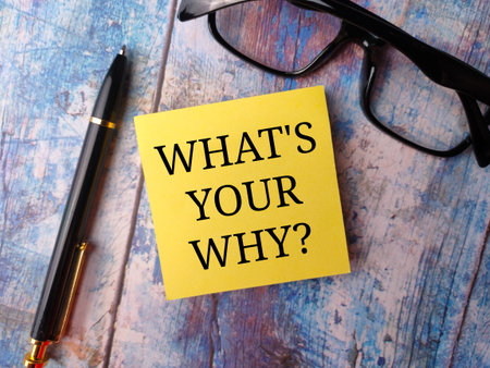 Sticky note and glasses with the word WHAT YOUR WHY on a wooden background