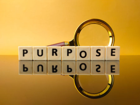 Toys word and magnifying glass with text PURPOSE on yellow background with reflection on a black acrylic boardの写真素材