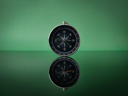 Closeup compass on green background with reflection on a black acrylic boardの写真素材