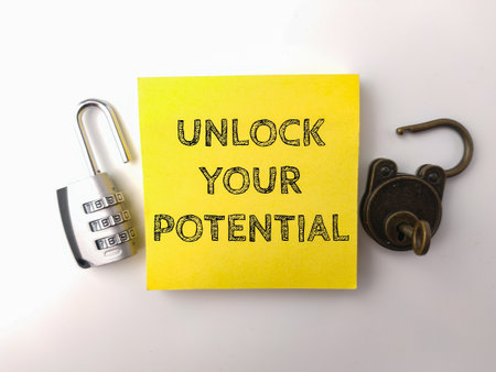 Padlock and sticky note with the word UNLOCK YOUR POTENTIAL  on a white backgroundの写真素材