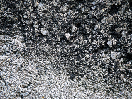 Closeup of the stone cement wall surface which has two tones of color which are black and white