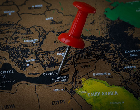 Close up red push pin pointing LEBANON ISRAEL word on a world map.