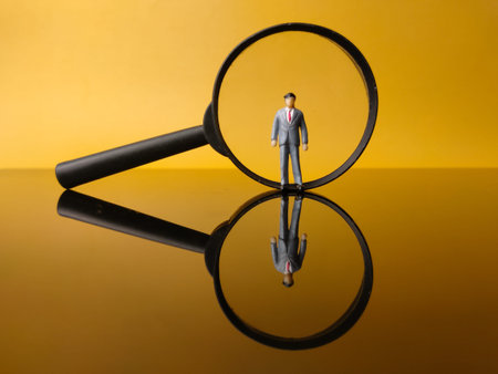 Miniature people and magnifying glass with reflection on a yellow backgroundの写真素材