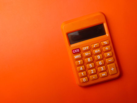 Top view orange calculator on a orange background with copy and text space.