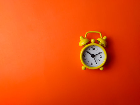Top view yellow clock on a orange background with copy and text space.の写真素材