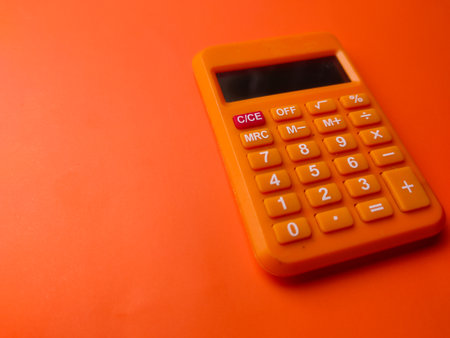 Closeup orange calculator on a orange background with copy and text space.の写真素材