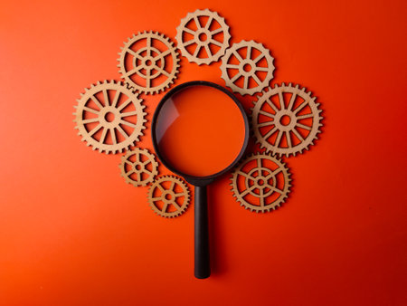Top view magnifying glass and wooden gear on an orange background.Business concept.の写真素材
