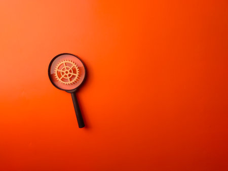 Top view magnifying glass and wooden gear on an orange background with copy space.の写真素材