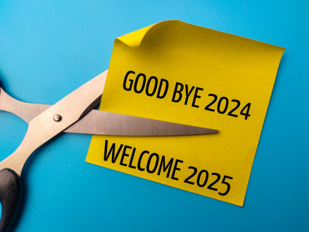 Sticky note and scissors with text good bye and welcome 2025 on a blue background. Business concept.の写真素材