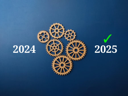 Wooden gear with text 2024 and 2025 with green right symbol on a blue background. Business concept.の写真素材