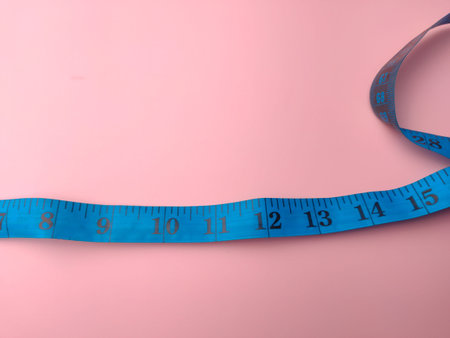 Closeup blue measuring tape on a pink background. Medical and health concept.
