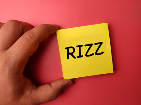 Someone hand holding sticky note with the word RIZZ on a red background.の写真素材