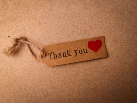 Brown card with the word Thank you on a wooden background.
