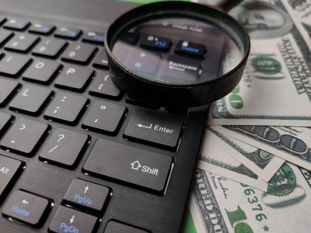 Closeup magnifying glass, banknote and keyboard business online concept.