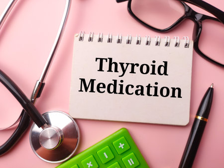 Notebook and doctor's equipment with the word Thyroid Medication on a pink background.の写真素材