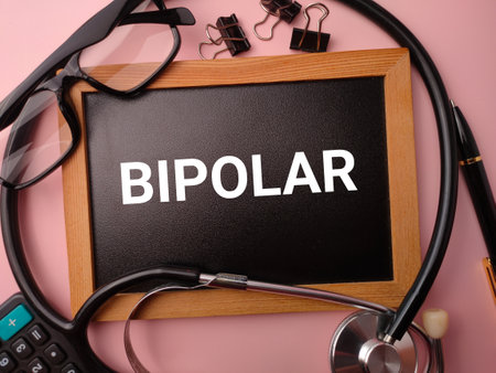 Wooden board and doctor's equipment with the word BIPOLAR on a pink background.の写真素材
