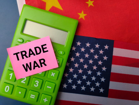 Top view calculator and sticky note with the word TRADE WAR on a us america and china flag background.Geopolitical Concept.の写真素材