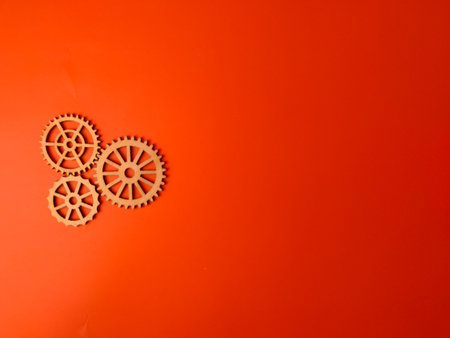 The image shows three wooden gears arranged on an orange background.の写真素材