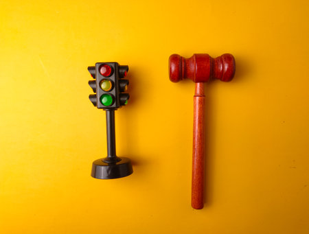 The image shows a miniature traffic light and a gavel on a yellow background.の写真素材