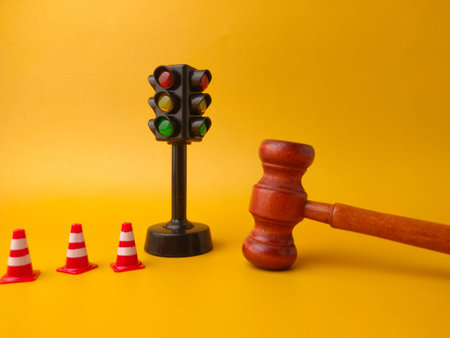 The image shows a miniature traffic light, small traffic cones, and a gavel. This combination of...