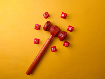 The image shows a wooden gavel surrounded by several small traffic cones on a yellow background.の写真素材