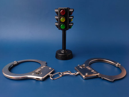The image shows a pair of handcuffs and a toy traffic light on a blue background.