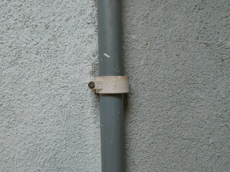 The image shows a PVC pipe with a pipe clip or saddle clamp. This type of clamp is used to secure the pipe to a wall or other surface.の写真素材