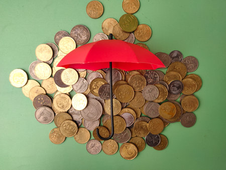 The image of an umbrella covering a pile of coins is a common visual metaphor for financial concepts.の写真素材