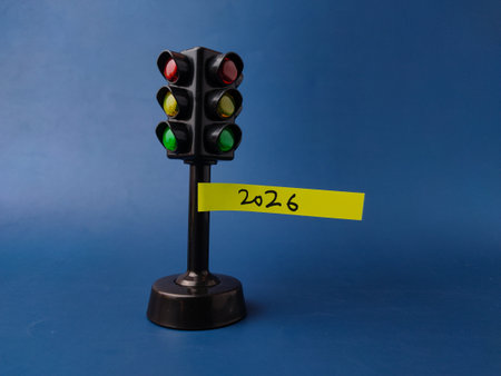 This image features a miniature traffic light toy with a yellow sticky note attached to its pole...