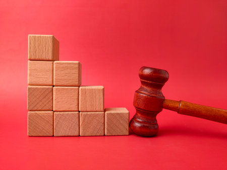 The image displays a wooden gavel next to a stack of wooden cubes on a red background.の写真素材