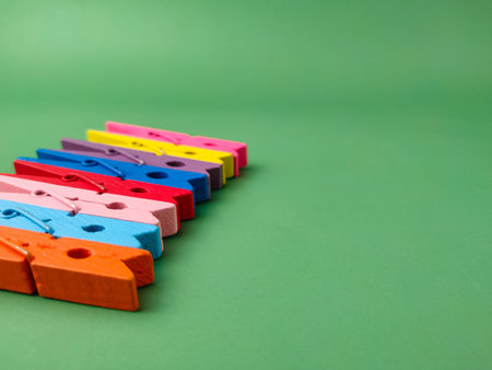 The image shows a row of colorful wooden clothespins on a green background.の写真素材