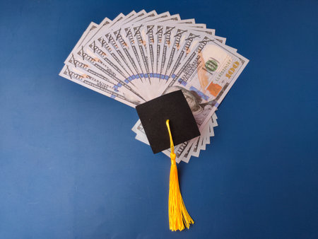 The image combines symbols of academic achievement (the graduation cap) with currency (U.S. dollars)の写真素材