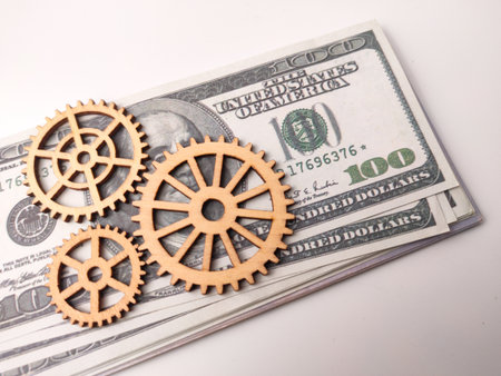 Three wooden gears resting on a stack of US one-hundred dollar bills.の写真素材
