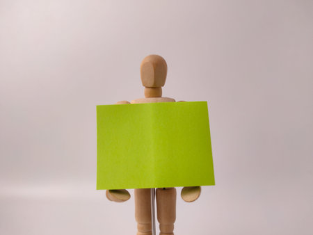 This image features aÂ wooden artist's mannequinÂ holding a blank, lime-green sign.