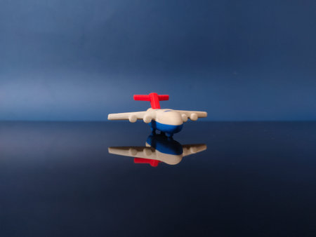 This is a miniature toy airplane eraser in white, blue, and red colors with reflection on dark blue...