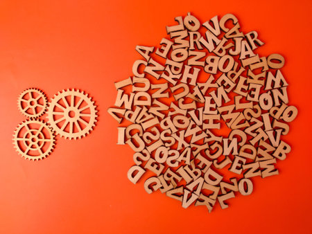 Wooden cut-out alphabet letters and gear shapes set against an orange background.