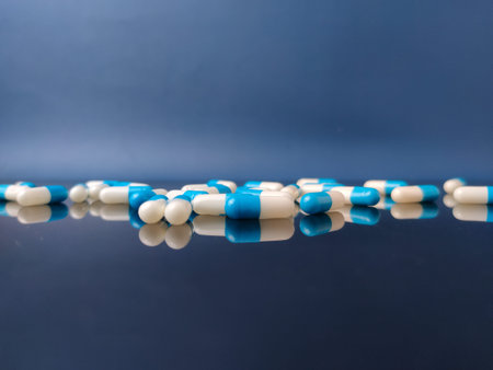 These are blue and white pharmaceutical capsules with reflection on blue background.