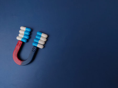 Medical capsules being attracted by a magnet on a blue background.