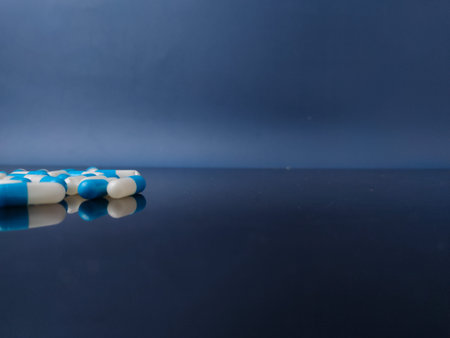 These are blue and white pharmaceutical capsules with reflection on blue background.の写真素材