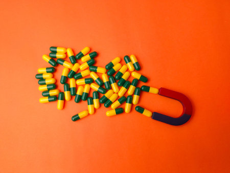 Horseshoe magnet attracting green and yellow medicine capsules.