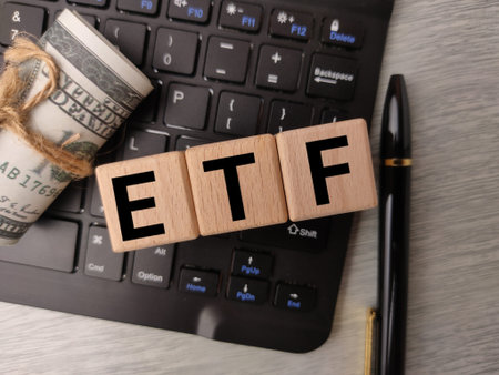 Word ETF formed by wooden blocks placed on a keyboard next to a roll of cash.