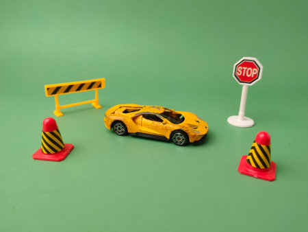 Miniature yellow car setup with cones, a barricade, and a STOP sign on a green background.
