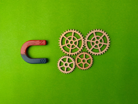 Magnet attracting a series of wooden gears on a green background.
