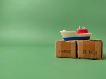 Two miniature shipping boxes, one topped with a toy ship on green background.