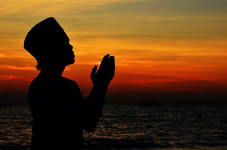 Silhouette of a Muslim praying during sunsetの写真素材