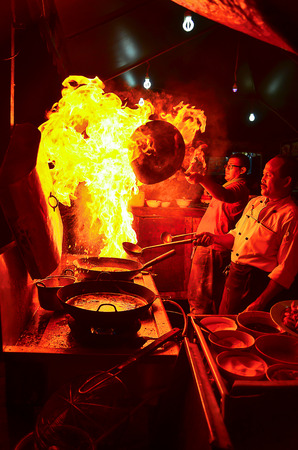 Sabah, Malaysia  June 27, 2013. Two chefs are cooking in the kitchen. Normal moment at the seafood restaurant in Kota Kinabalu, Sabah. Cooking with dramatic flame is done to attract the customers.のeditorial素材