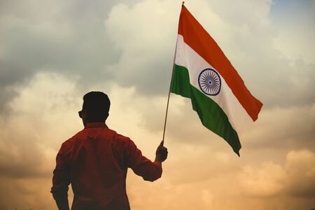 silhouette of Guy holding Indian flag in dramatic backgroundの写真素材