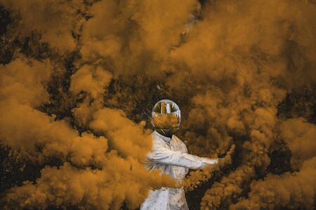 guy in mask standing in between orange brown smoke bombsの写真素材