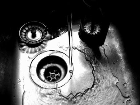 mess in the kitchen sink and tab water flowingの写真素材